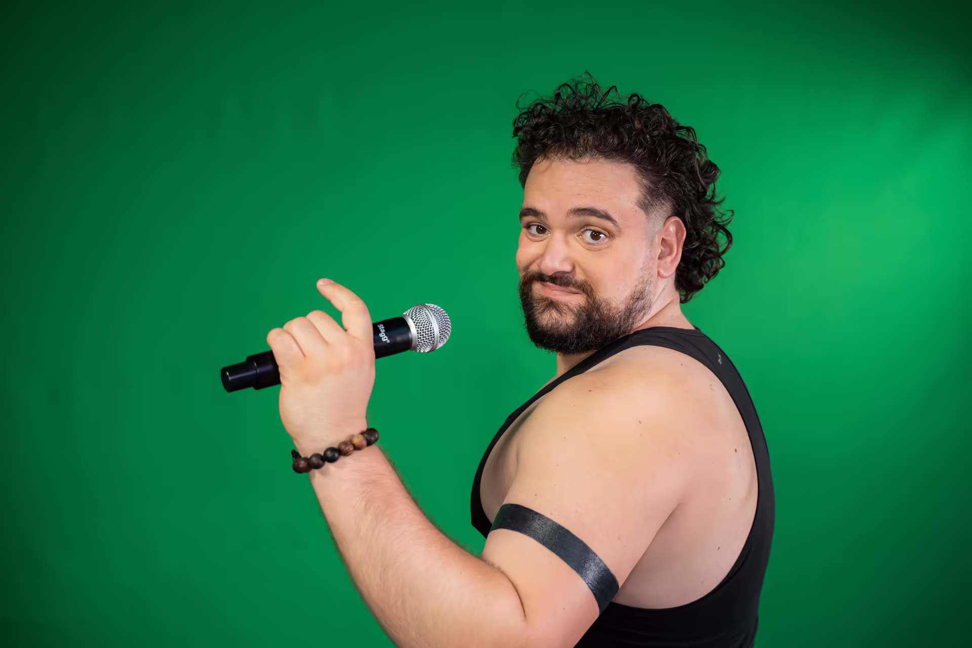 Arsenii Stanis holding a microphone against a green backdrop