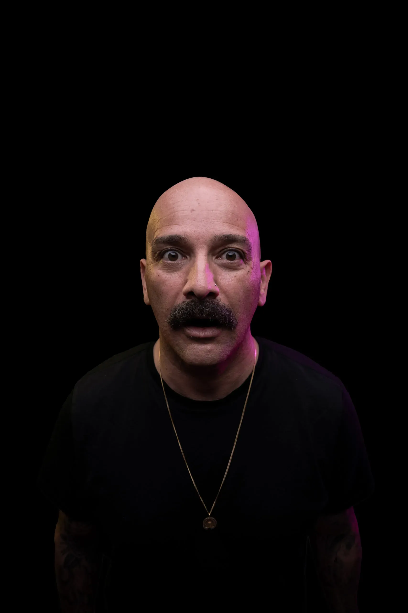 Tamer Kattan looking into the camera under magenta stage light