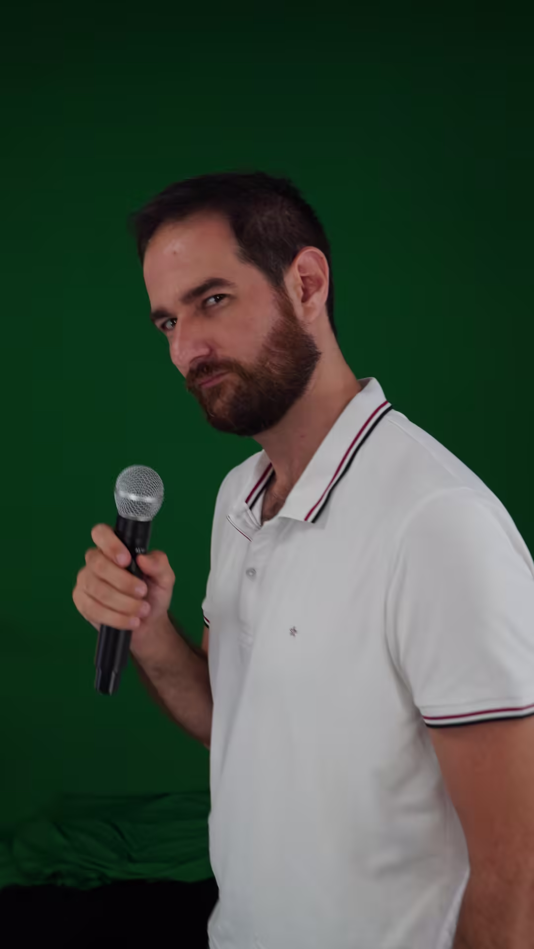Younes holding a microphone against a green backdrop