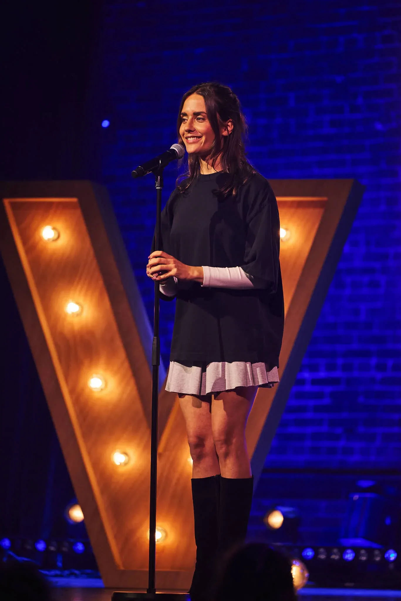 Fiona G smiling onstage beside a microphone